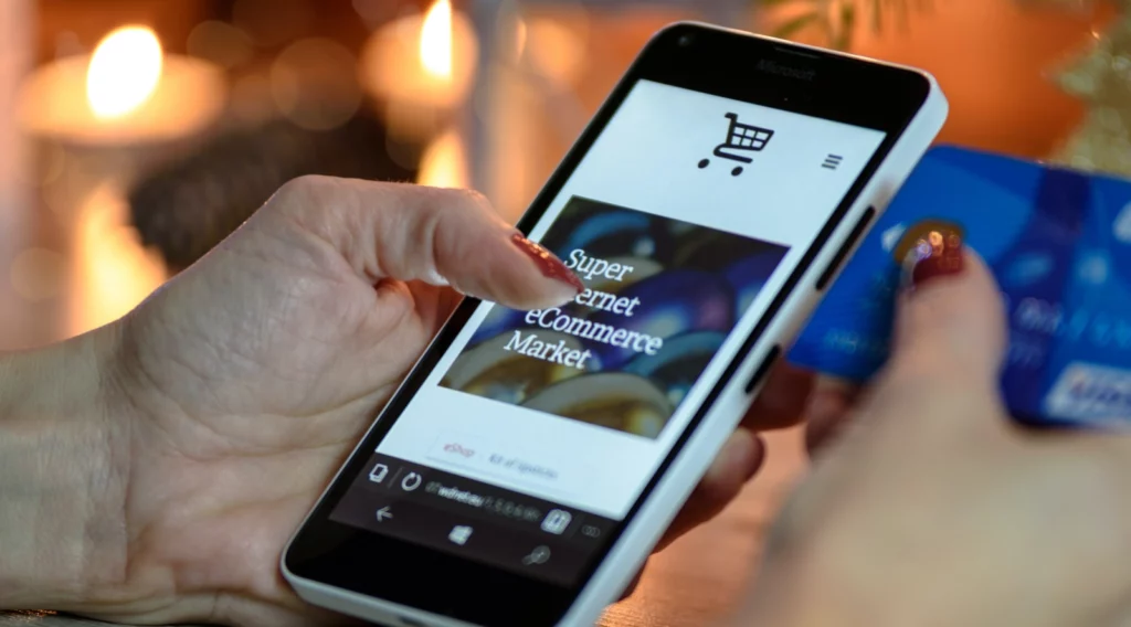 Cropped hand holding mobile to pay for ecommerce product