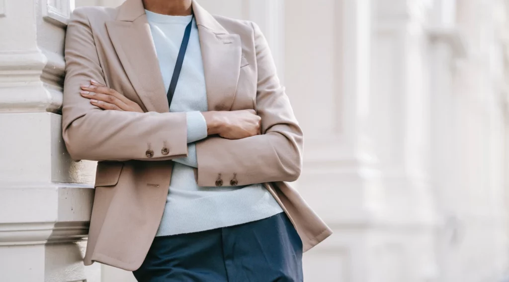 Cropped working lady in a brown blazer folding her arms